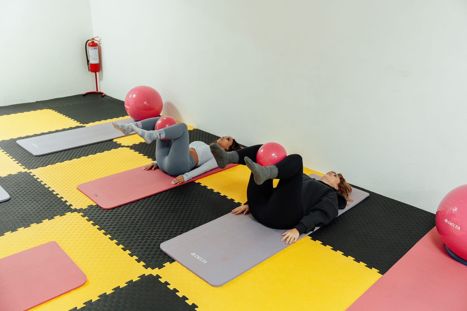Drei Teilnehmerinnen trainieren mit Gymnastikbällen auf Matten in einem Kursraum – bezuschusst wird der zertifizierte Kurs, nicht die Studio-Mitgliedschaft.