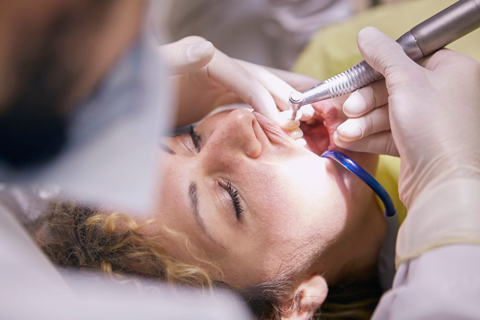 Zahnärztin reinigt in der Praxis mit einem Handinstrument die Zähne einer Patientin