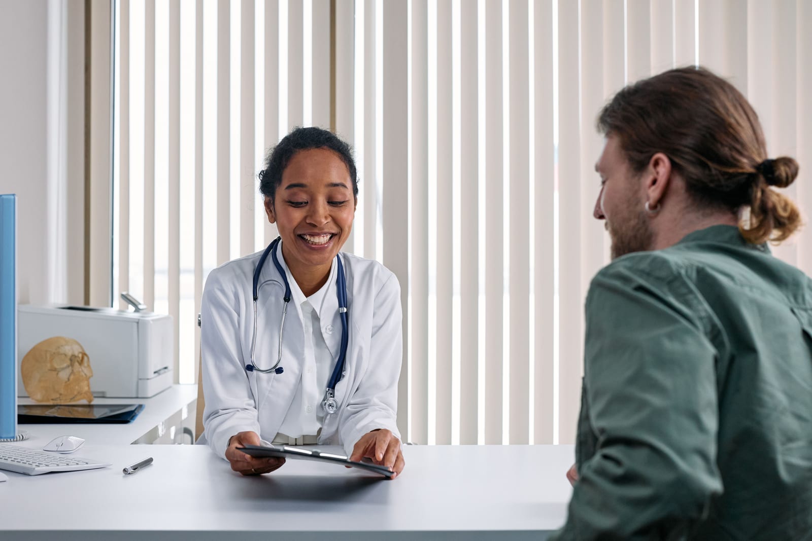 Arzt und Patient führen ein Gespräch über die Kostenübernahme in einer hellen Klinik.
