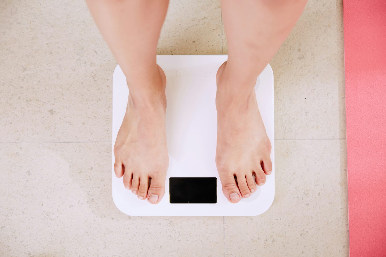Eine Person steht auf einer digitalen Personenwaage im Badezimmer.