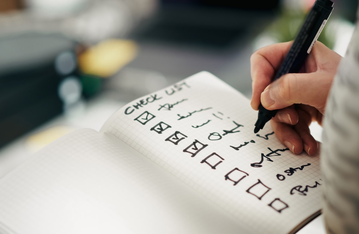 Hand hakt mit einem schwarzen Stift Punkte auf einer handgeschriebenen Checkliste ab