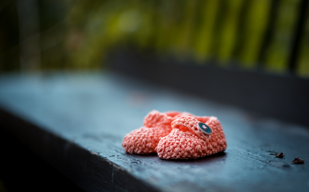 Gestrickte rosa Babyschuhe auf einer dunklen Holzbank