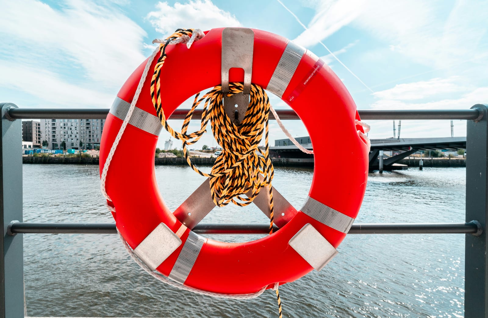 Ein Rettungsring hängt an einem Geländer über dem Wasser.