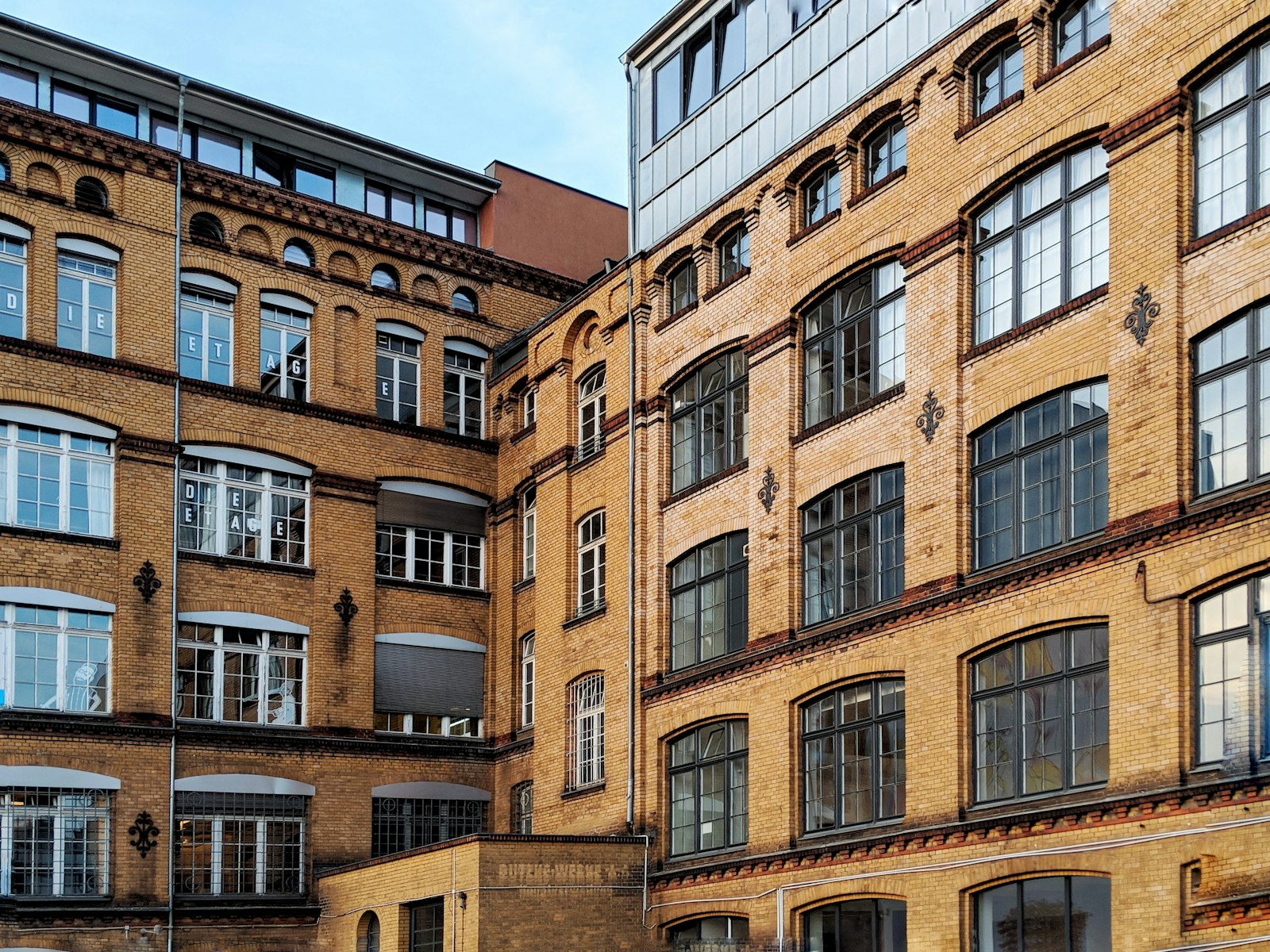 Backsteinfassaden zweier gründerzeitlicher Gewerbehöfe mit hohen Sprossenfenstern