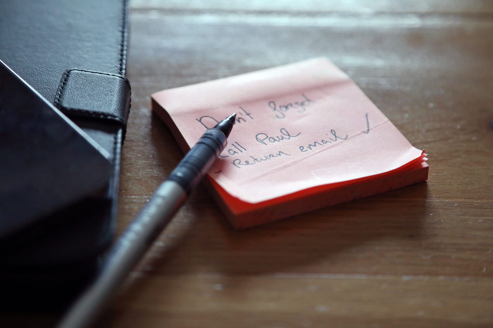Haftnotizen mit einer To-do-Liste, Stift und Unterlagen auf einem Schreibtisch.