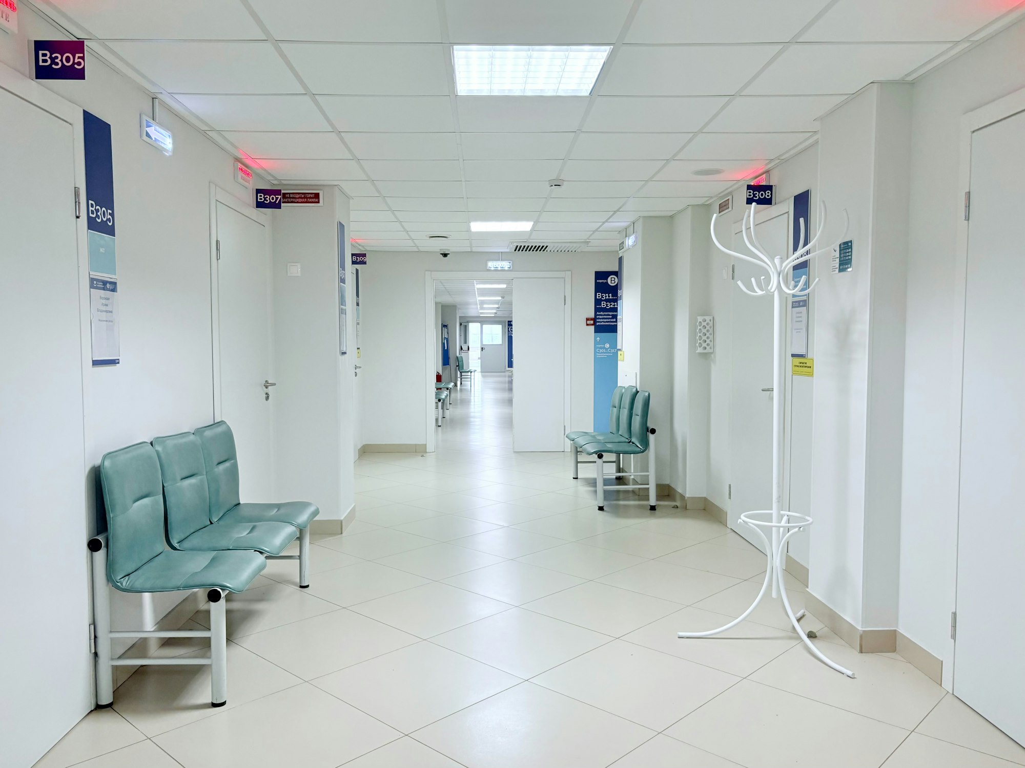 Ruhiger Klinikflur mit Sitzbänken und Behandlungszimmer-Türen