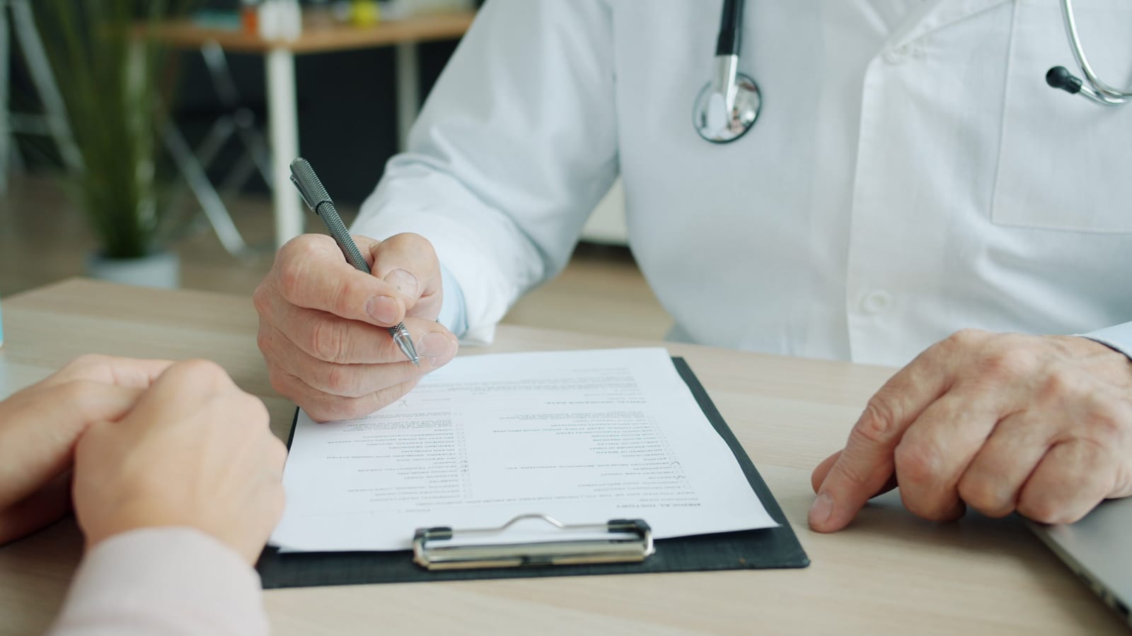 Arzt und Patient sehen gemeinsam medizinische Unterlagen während eines Gesprächs durch.